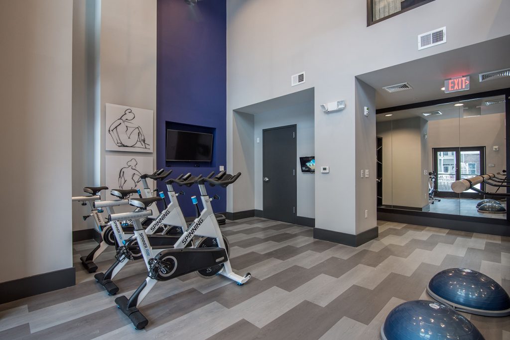 Community fitness center with spin bikes and wall-mounted TV