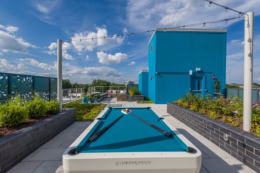Pool table on rooftop terrace with festival lighting and planters