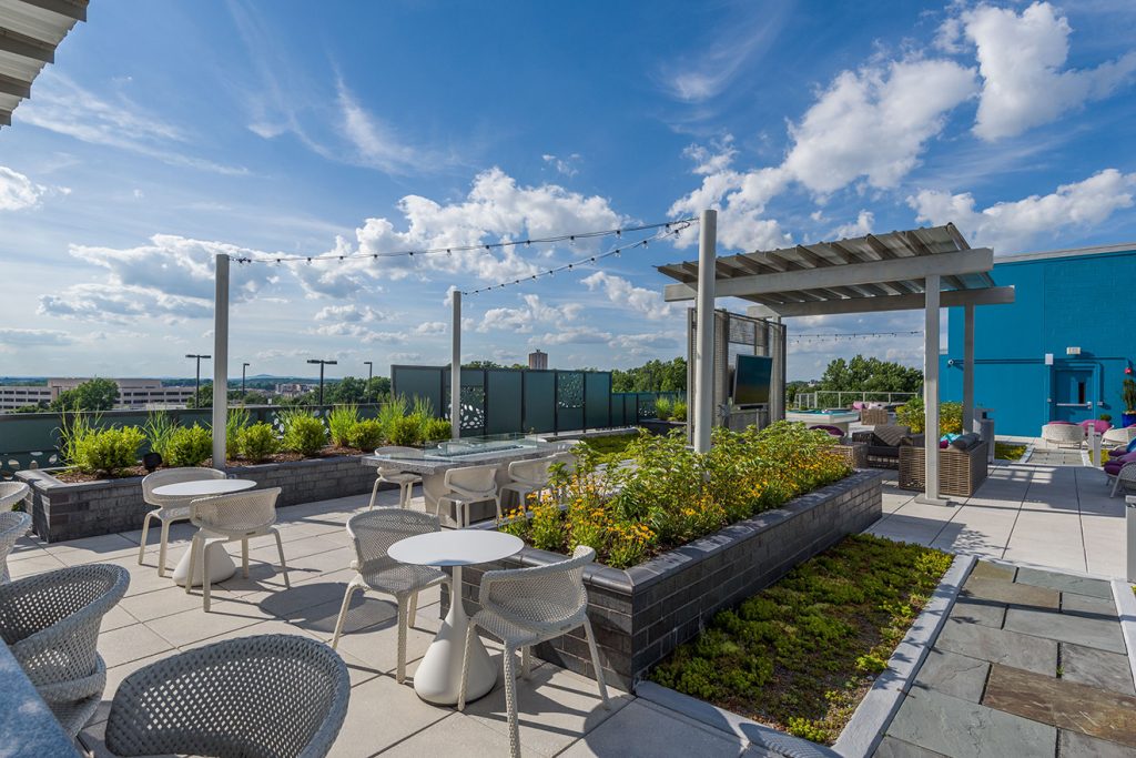 Rooftop lounge with outdoor seating, festival lighting, and community garden planters