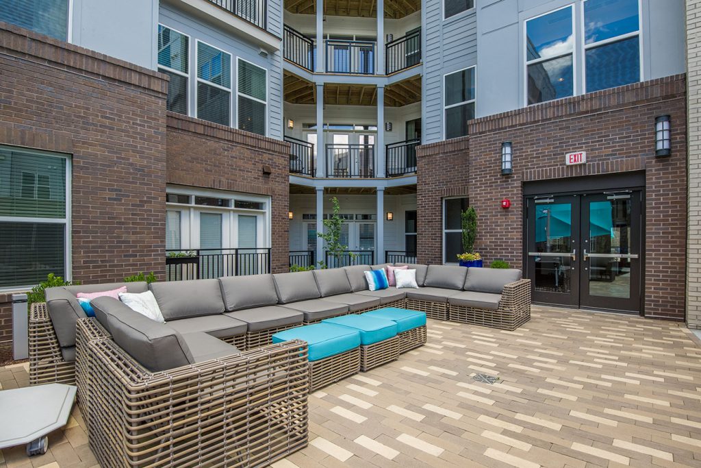 Outdoor courtyard seating with large sectional sofa near apartment balconies