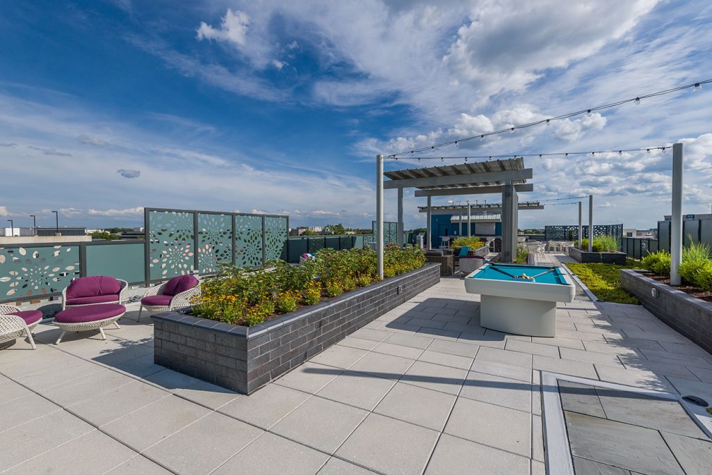 Rooftop terrace with pool table, covered lounge areas, and festival lighting