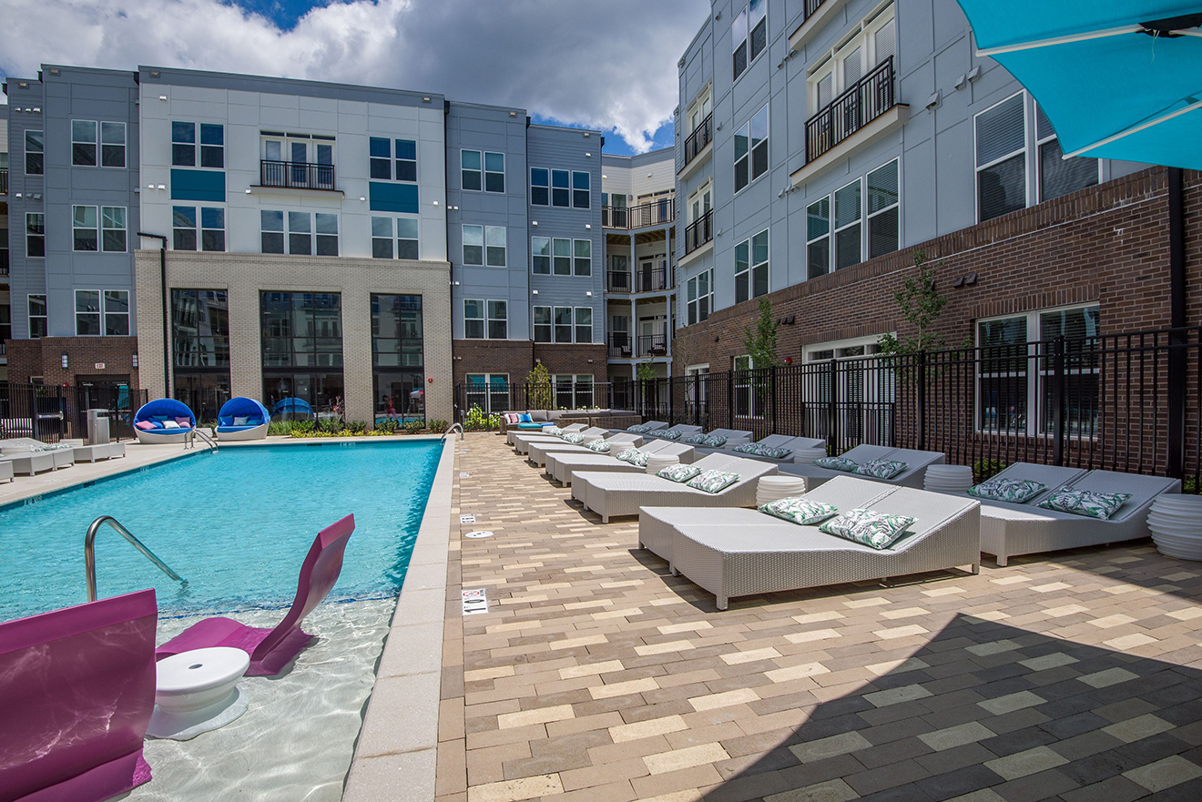 Pool courtyard with comfortable seating and long chairs on deck and in-pool loungers.