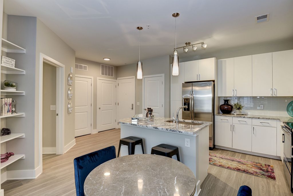 Model apartment with kitchen island, built-in bookcases, and wood-style flooring