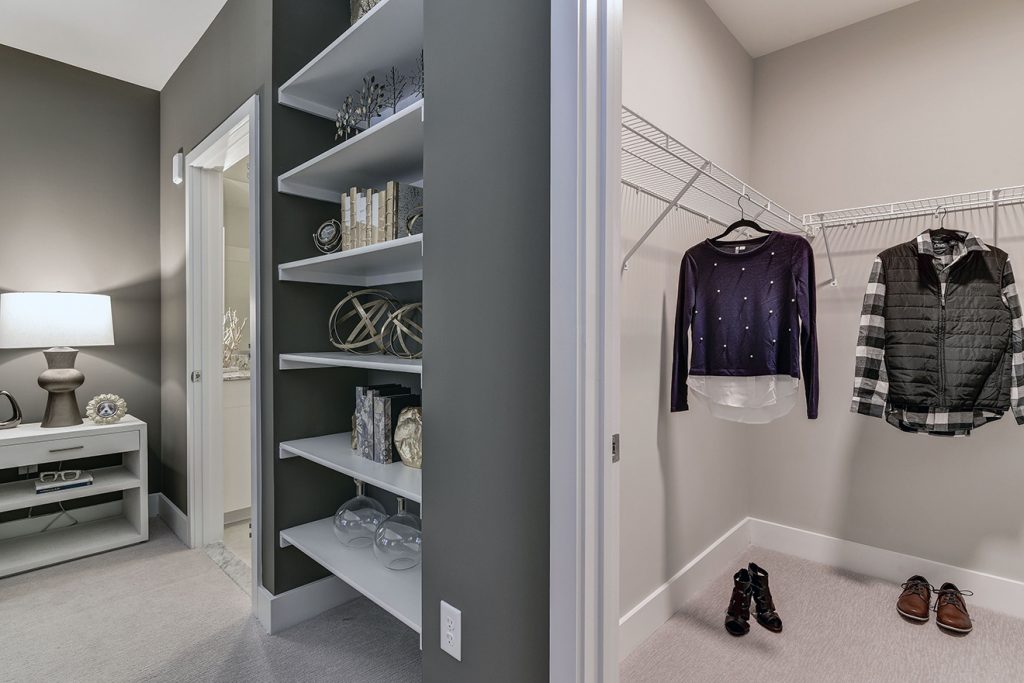 Built-in storage bookcases in model apartment bedroom near walk-in closet