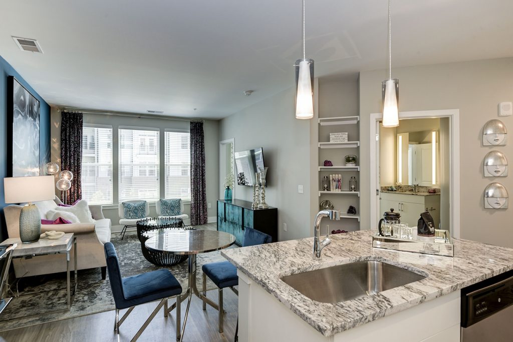 Model apartment with kitchen island, small dining set, built-in bookcase, and large windows