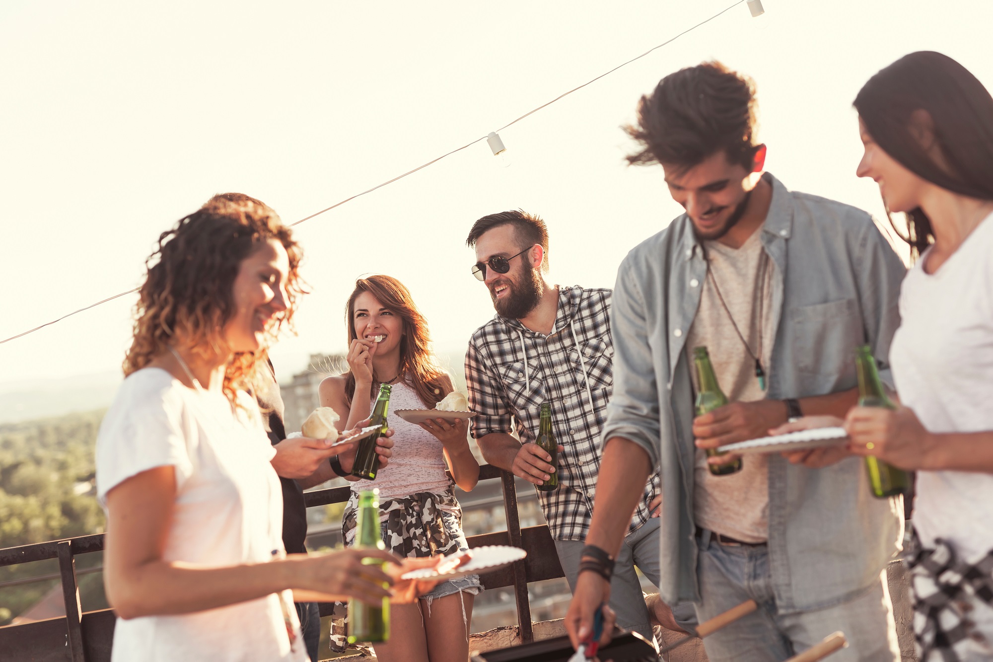Group of people drinking beer and enjoying food on rooftop