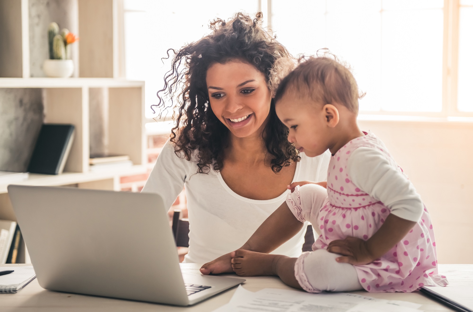 Woman and small baby looking at laptop screen in living room