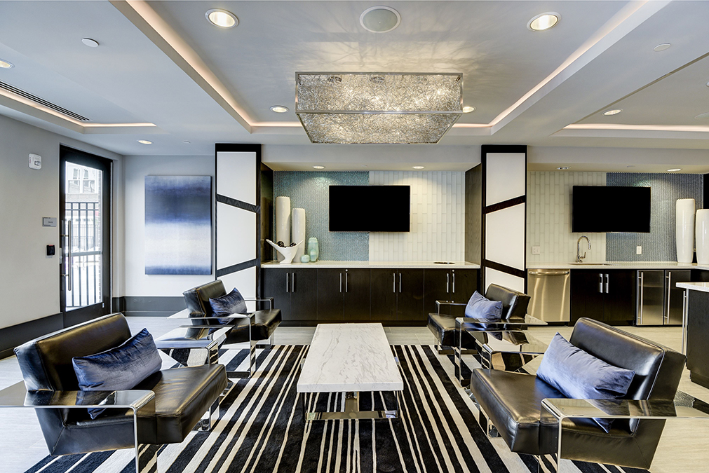 Clubroom lounge seating area near demonstration kitchen with wall-mounted TV